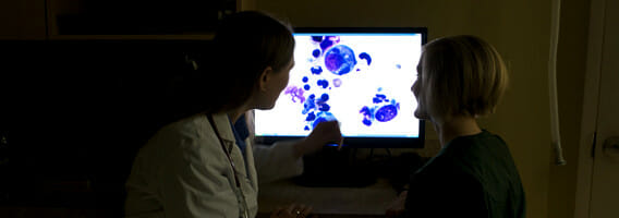 Two people looking at a monitor with a lab test image
